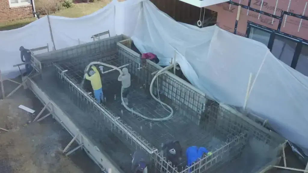 Aerial view of the crew working around a rebar-framed pool shell at the water's edge
