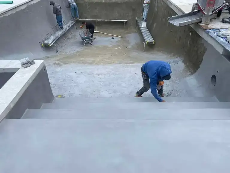 Interior finishing work on a pool shell, a worker laying the surface