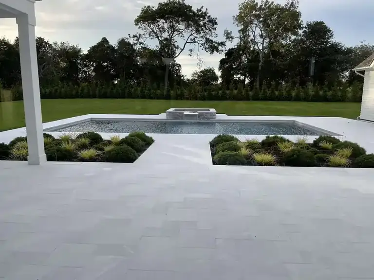 Long pool set into planting beds beside a white columned house