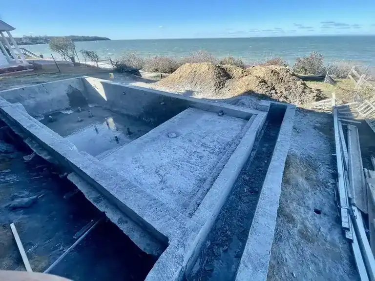 New pool shell formed on a waterfront lot, the bay beyond the dig
