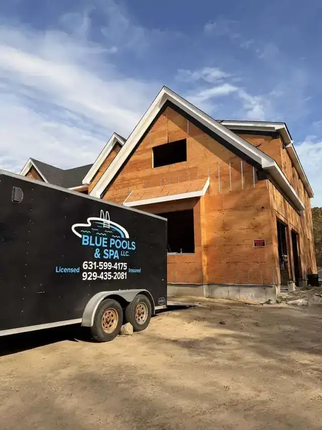 Black Blue Pools & Spa work trailer parked at a job beside a timber-frame house