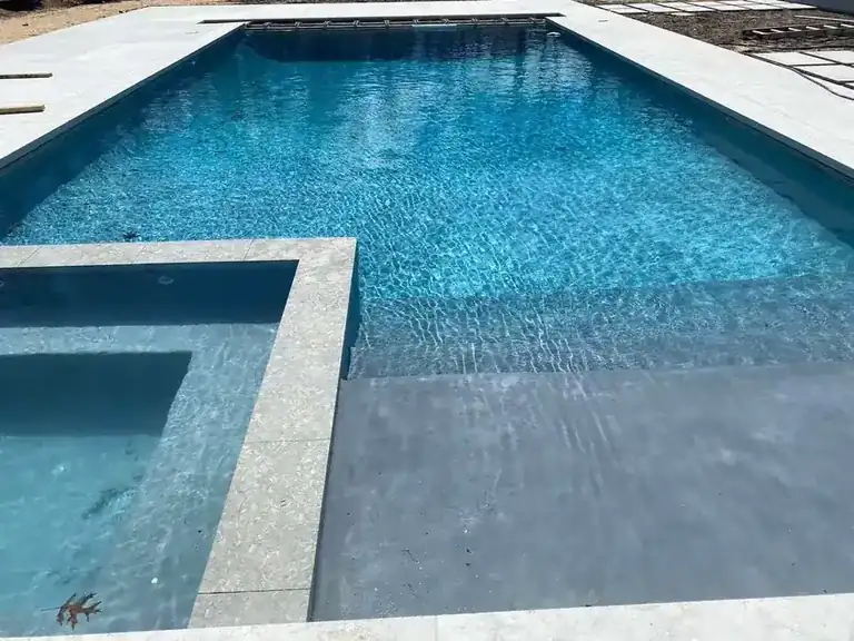 Pool beside a raised spa, clear water over the bench and entry steps