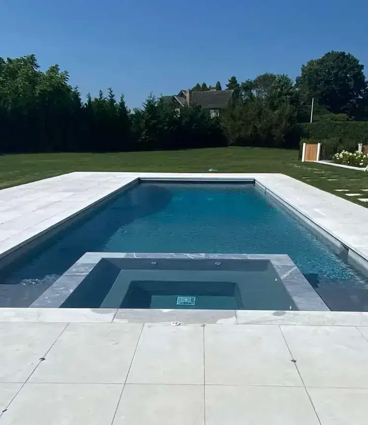 Raised square spa at the end of a rectangular pool, stone coping all round