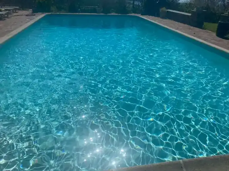 Sunlight rippling across clear pool water over a blue finish