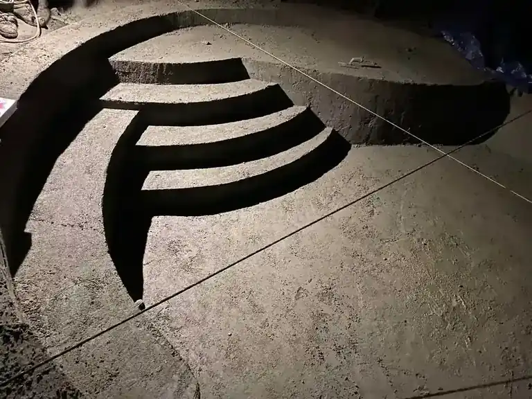 Pool shell at the shotcrete stage, curved concrete steps formed into the bench and string lines still in place